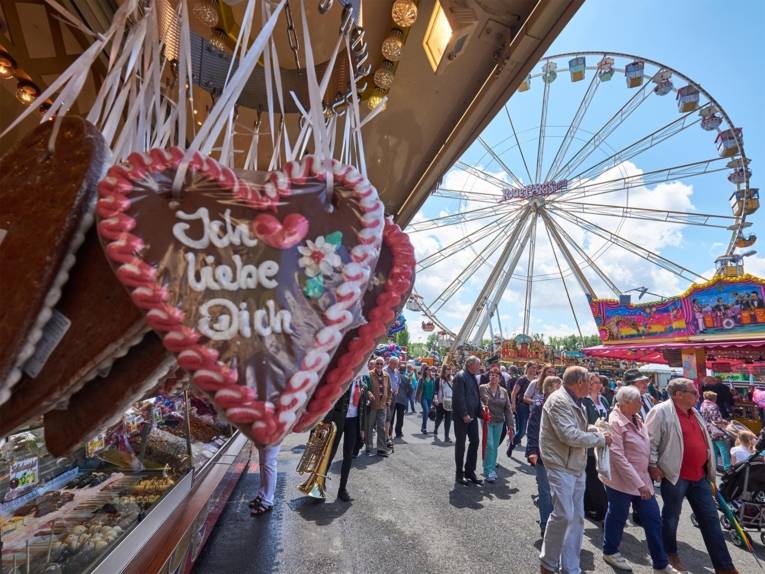 Menschen - auf dem Schützplatz flanierend, im Vordergrund ein Verkaufsstand mit Lebkuchenherzen.