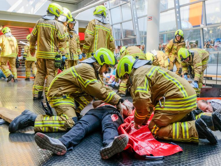 Einsatzkräfte übernehmen die vorgesichteten Patienten und bereiten den Transport in eine Patientenablage vor.