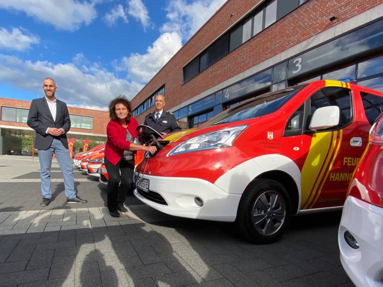 Ein E-Fahrzeug der Feuerwehr Hannover mit Personen im Vordergrund