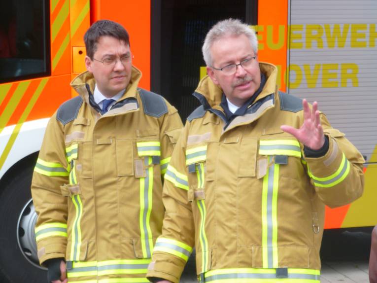 Finanz-, Rechts-, und Ordnungsdezernent Dr. Hansmann und Direktor der Feuerwehr Lange stellen die neue Schutzkleidung vor