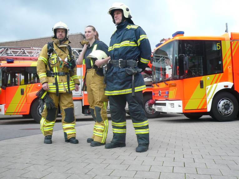 Michael Hirt, Janina Poletschny und Philip Reime zeigen zum Vergleich die neue und alte Feuerwehrschutzkleidung