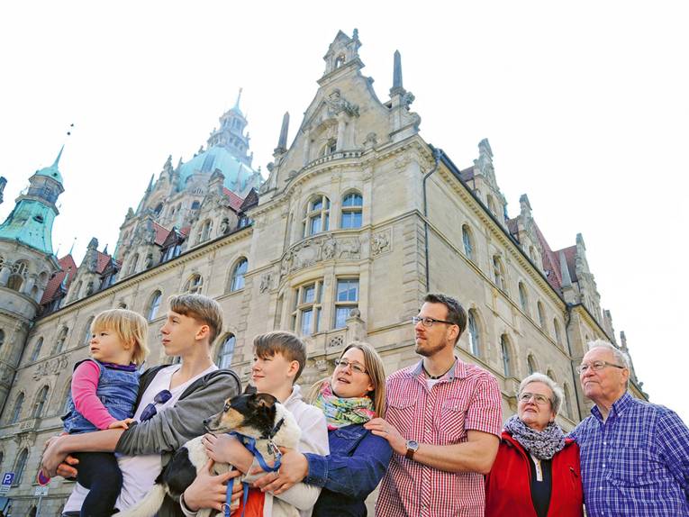 Eine Familie bestehend aus drei Generationen und einem Hund vor dem Rathaus in Hannover