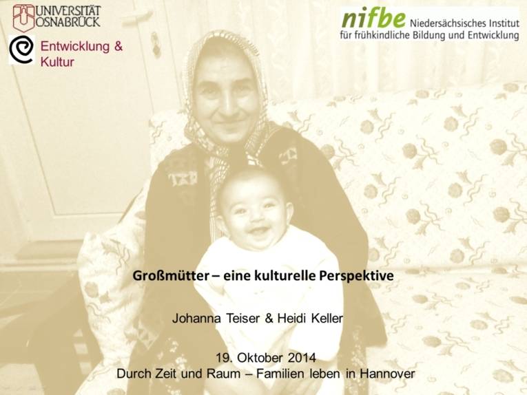 Titelseite einer Präsentation mit dem Titel "Großmütter - eine kulturelle Perspektive". Abgebildet ist eine ältere Frau mit Kopftuch, die auf einem bunt gemusterten Sofa sitzt und ein Kleinkind auf dem Schoß hat. 