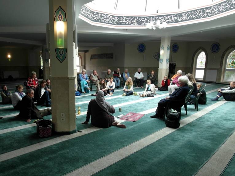Etwa 20 Besucher/innen sitzen mit der Referentin im Innenraum der Moschee im Kreis.