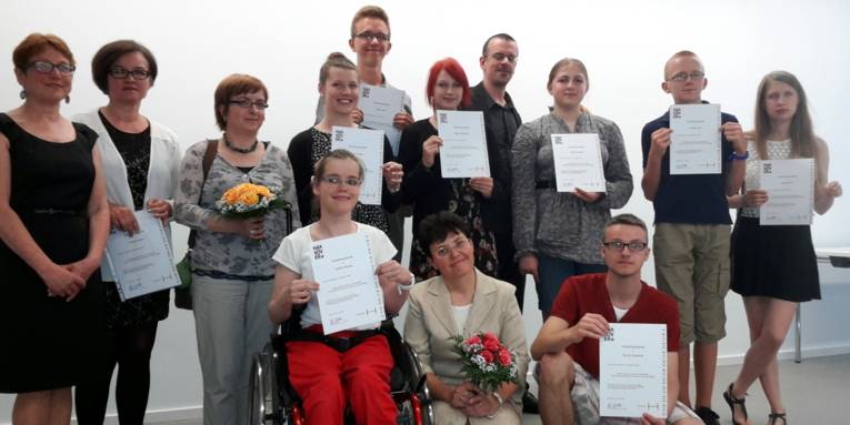 Etwa 15 Jugendliche und 2 Erwachsene stehen neben- und voreinander. Die Jugendlichen halten Urkunden in den Händen.