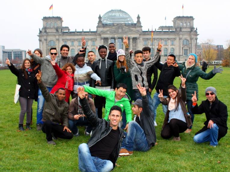 Eine 21-köpfige Gruppe posiert vor dem Bundestagsgebäude.