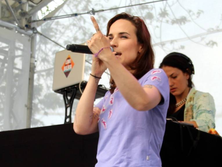 Eine Frau steht auf einer Bühne und singt in ein Mikrofon.