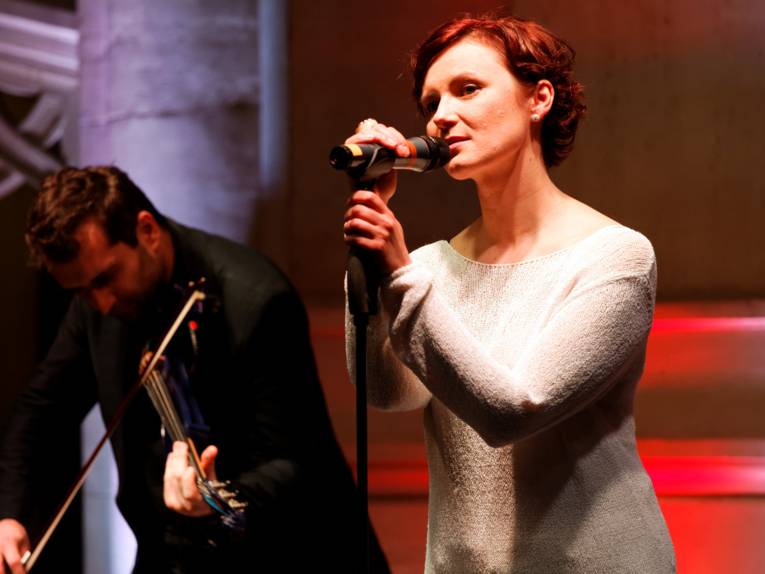 Anna Nova trägt den Song „Ich bereue nichts“ vor, im Hintergrund der begleitende Geiger