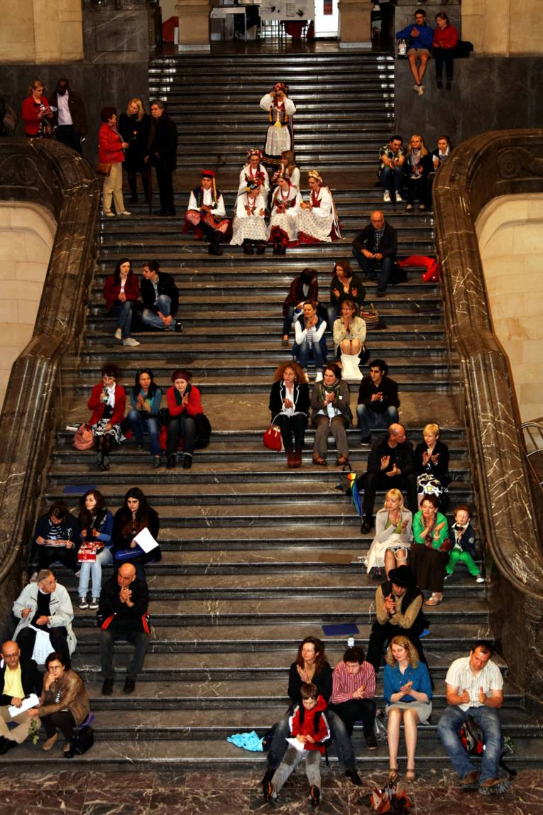 Auf der großen steinernen Treppe in der Rathaushalle sichern sich mehrere Dutzend Besucher/innen schon einmal Plätze für das Konzert