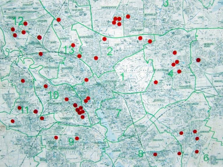 Eine schwarzweiße Stadtkarte füllt das Bild aus. Auf dieser Karte sind mit etwa 50 roten Punkten die Standorte von Rucksack-Projekten markiert.