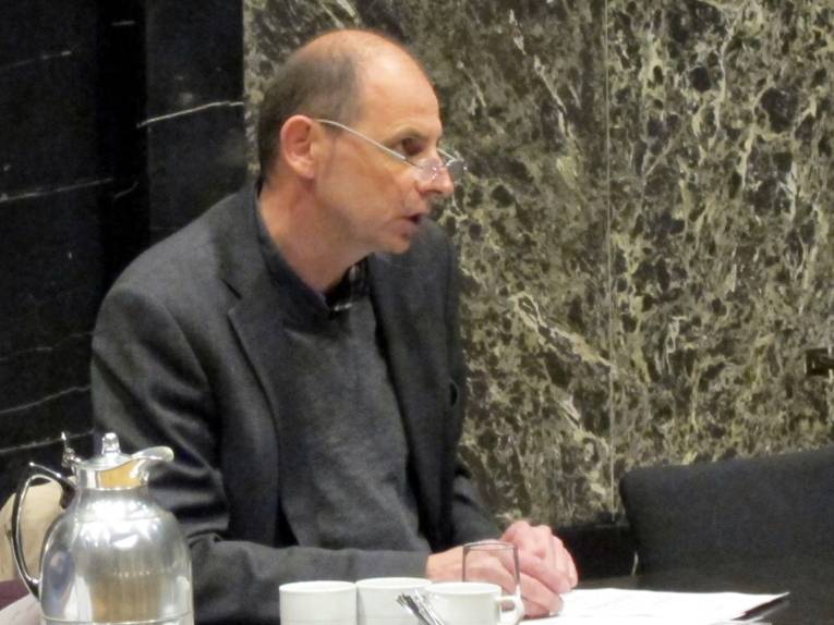 Ein Mann sitzt an einem Tisch und spricht.