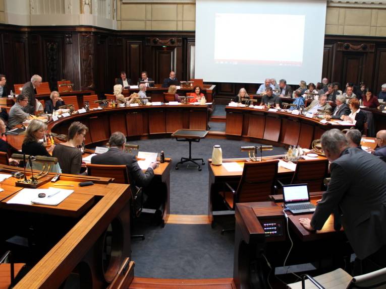 Etwa 40 Personen sitzen und stehen um die kreisförmig aufbauten Pulte im Hodlersaal.