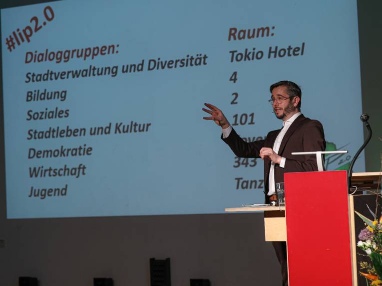 Ein Mann steht vor der Projektionsfläche eines Beamers, auf denen die LIP-Handlungsfelder mit den jeweiligen Raumzuordnungen dargestellt sind.