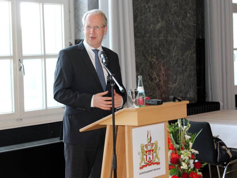 Ein Mann steht hinter einem Rednerpult und spricht.