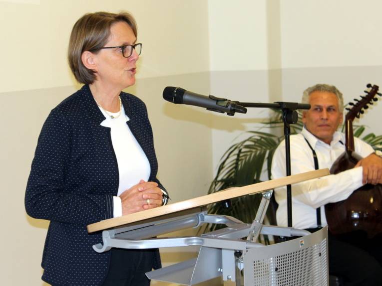 Eine Frau steht im Gartensaal des Neuen Rathauses hinter einem Rednerinnenpult und spricht in ein Mikrofon.