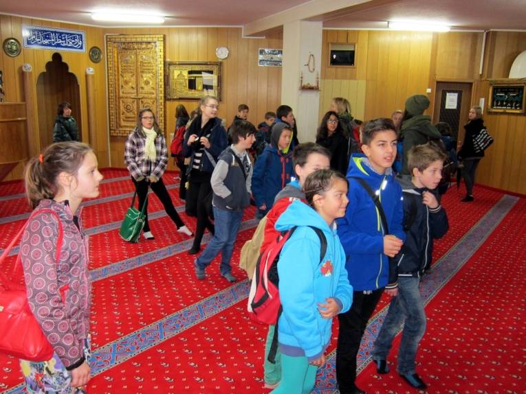Schüler/innen stehen im Gebetsraum der DİTİB-Moschee und sammeln Impressionen der islamischen Kultur