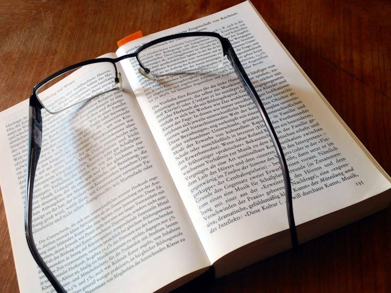Foto von einem Buch, auf dem eine Brille liegt.