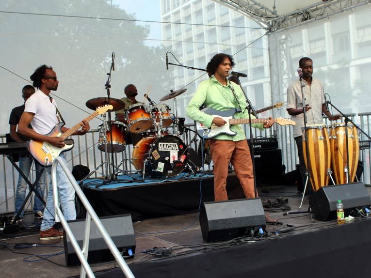Sechs Personen stehen mit unterschiedlichen Instrumenten auf einer Bühne.