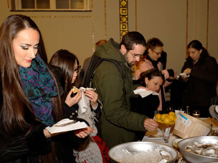 Mehrere Besucherinnen und Besucher bedienen sich am Austern-Buffet
