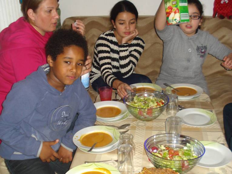 Kinder sitzen an einem gedeckten Tisch