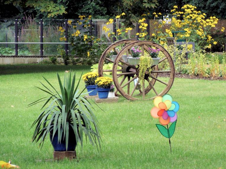 Ein mit Blumen geschmücktes Holzrad im Park des Pflegezentrums Heinemanhof