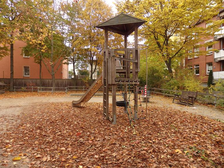 Holzspielgerät mit Rutsche auf einem herbstlichen Spielplatz
