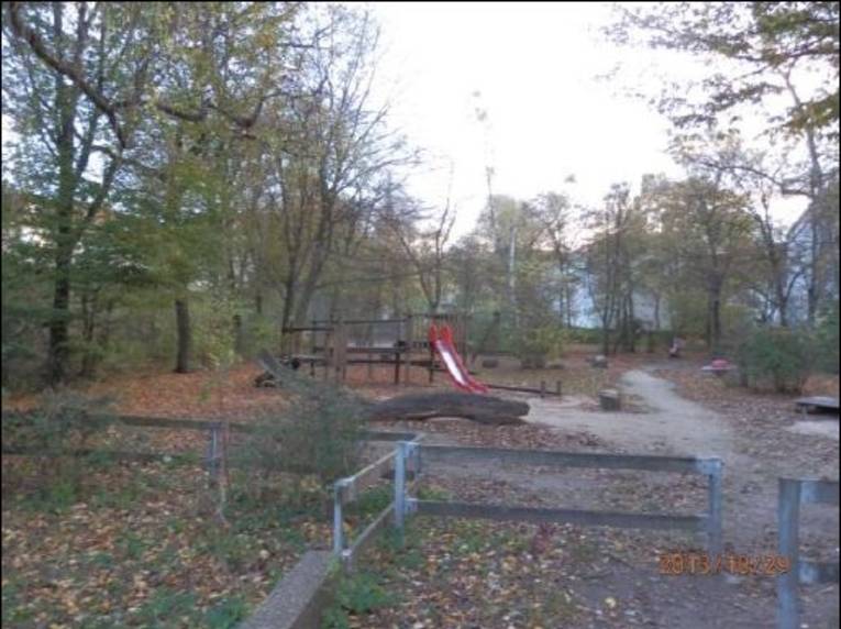 Spielplatz mit roter Rutsche und Holzspielgeräten

