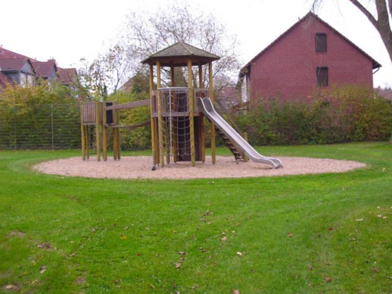 Ein Holzturm mit Klettermöglichkeit und Rutsche auf dem Spielplatz Emslandstraße