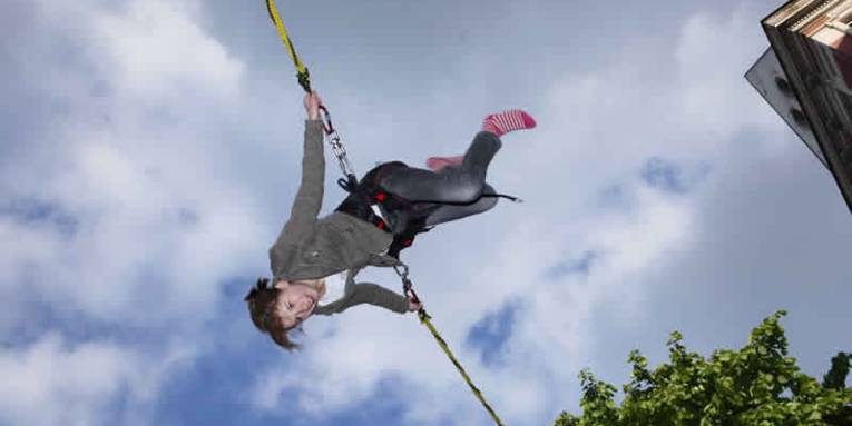 Eine junge Frau fliegt, gesichert durch zwei Seile, durch die Luft