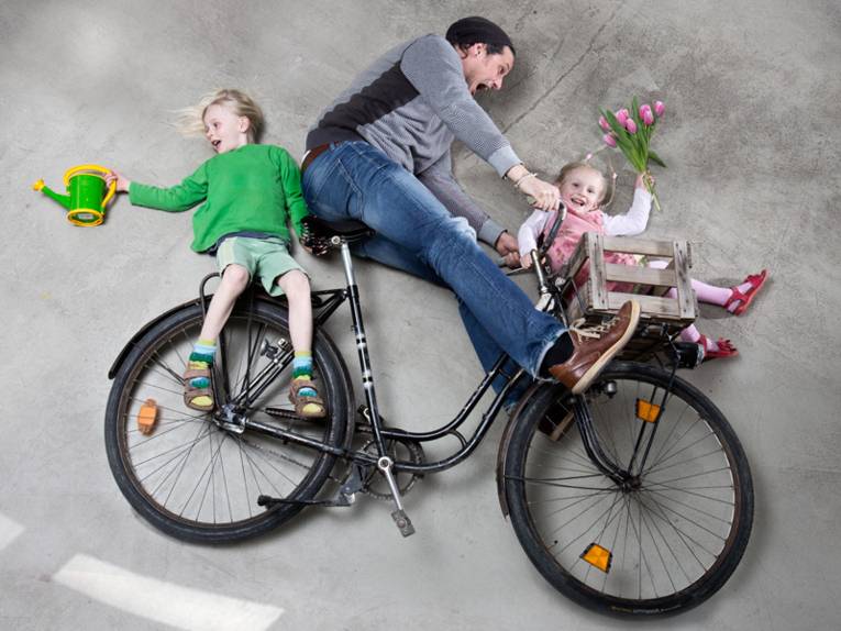 Vater transportiert zwei Kinder auf seinem Fahrrad