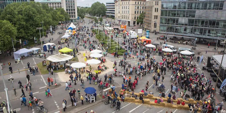 Fußgänger und Fahrradfahrer, Informationsstände und Heuballen, die zum Sitzen einladen, auf dem Aegidientorplatz