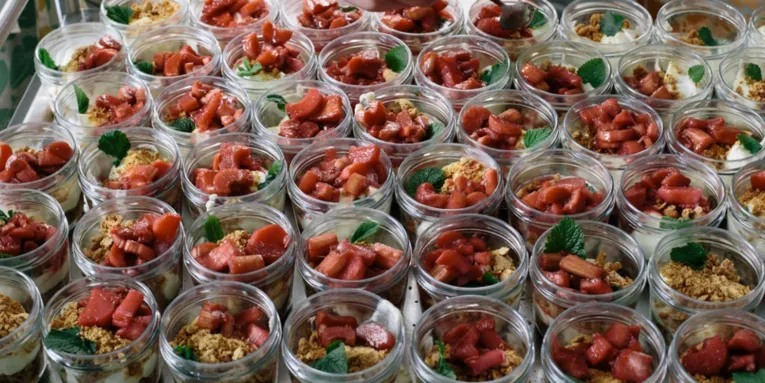 Viele Dessertportionen im Glas, die mit roten Früchten bedeckt sind
