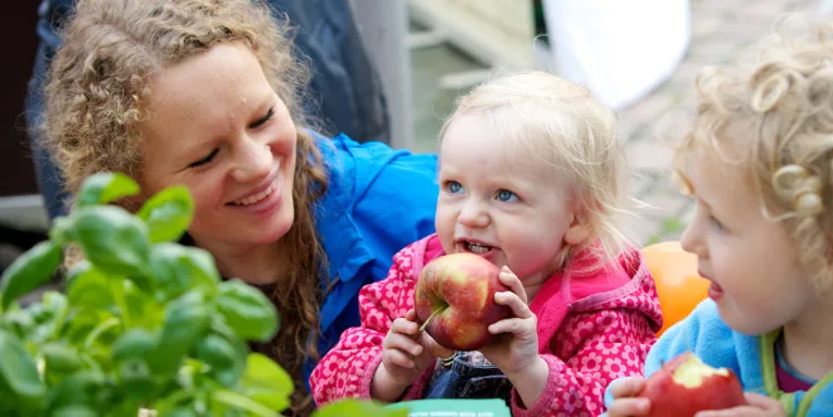 Junge Frau mit zwei Kindern, die Äpfel essen