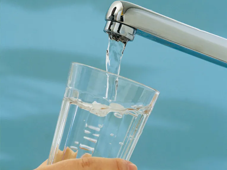 Wasserglas wird unter Wasserhahn gehalten