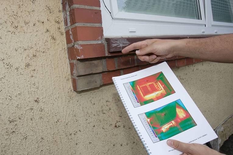 Hände mit Thermografiegerät vor Fenster