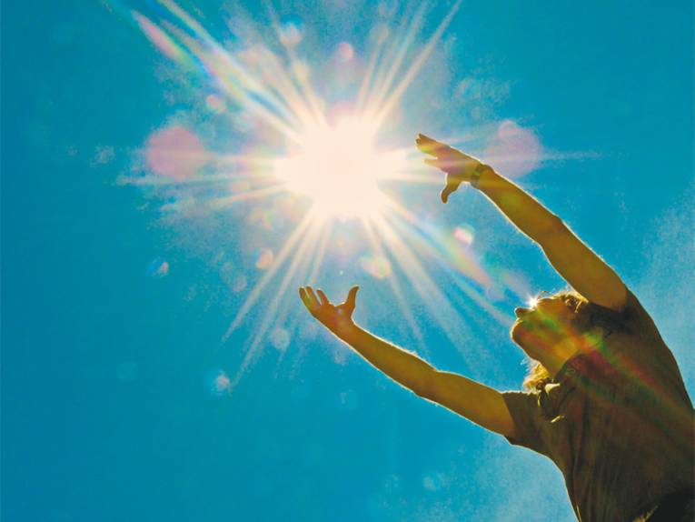 Mann streckt die Arme der Sonne entgegen