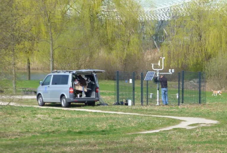 Wiese mit Weg am Kronsberg, im Hintergrund umzäunte Wetterstation mit Solarpaneel