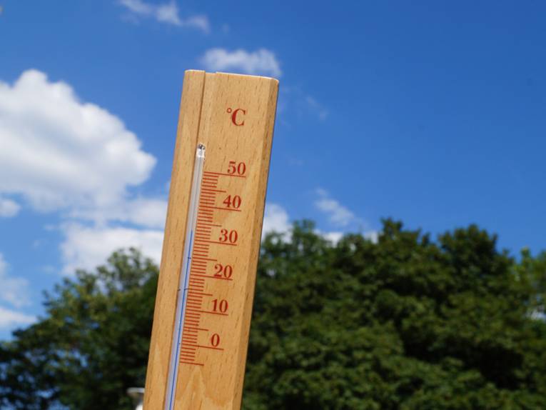 Ein Thermometer vor Sommerhimmel zeigt 32 Grad Celsius