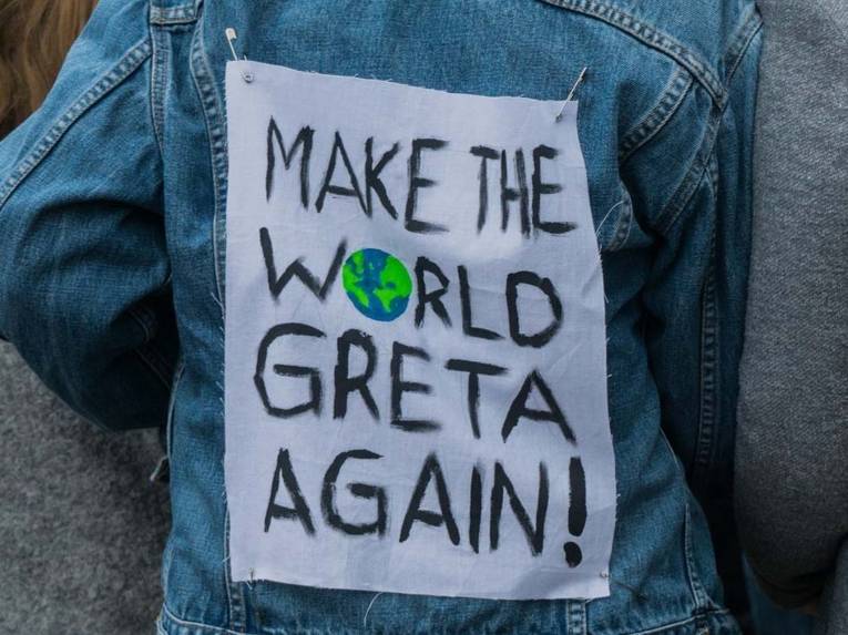 Eine Person von hinten, die eine Jeansjacke steht. Darauf steht "Make the world Greta again". 