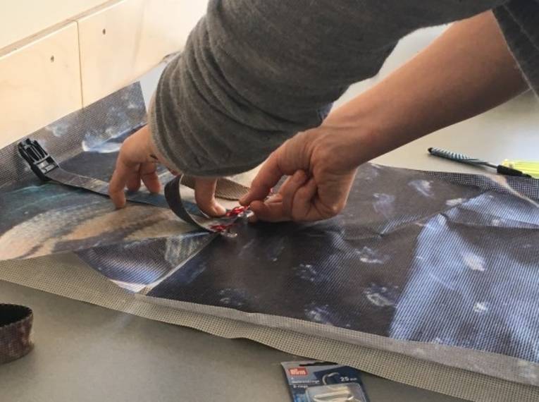 Eine Person fertigt aus einem Banner einen Ruksack