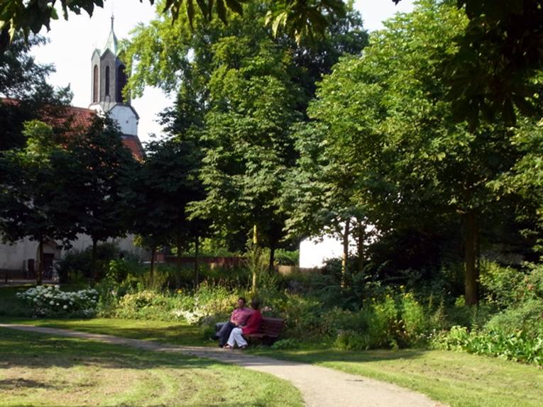 Blick in den Hinüberschen Garten, auf einer Parkbank sitzen zwei Personen