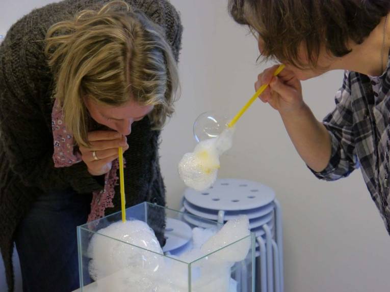 Zwei Frauen, die mit Wassergläsern experimentieren.