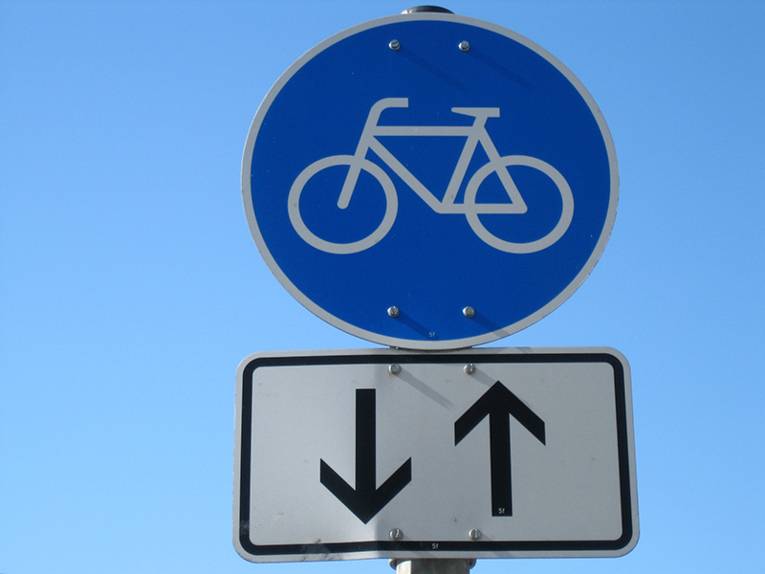 Blaues Hinweisschild mit Pfeilen für einen Fahrradweg in beide Richtungen