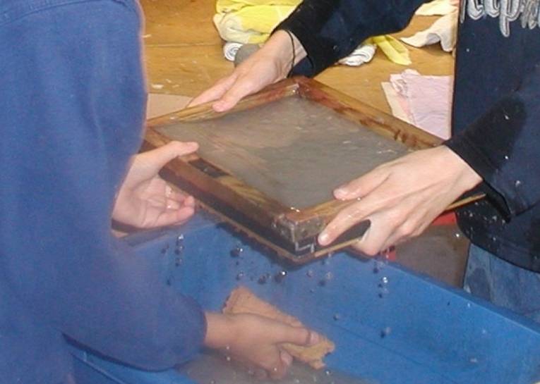 Hände, die ein Sieb zum Papierschöpfen halten