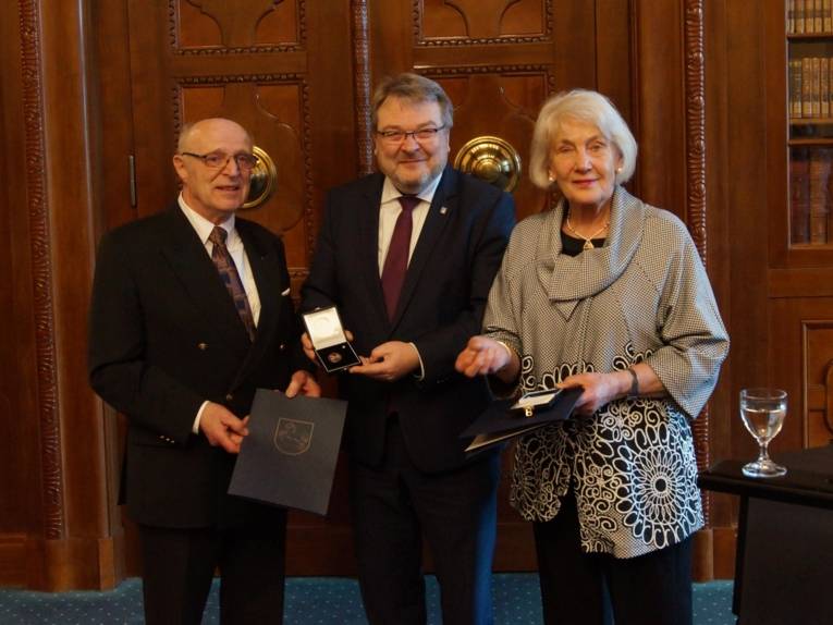 Zwei Männer und eine Frau mit Auszeichnungen. 