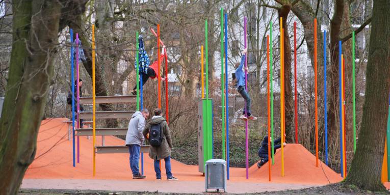 An bunten Stangen im Stadtteilpark Linden-Süd turnen Kinder unter Aufsicht von zwei Erwachsenen.