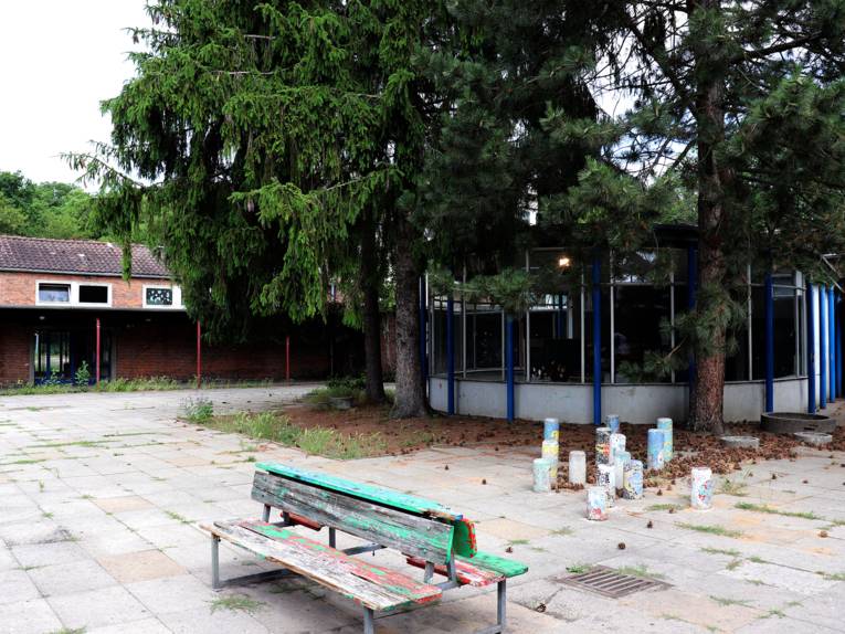 Innenhof der Paul-Dohrmann-Schule mit hölzerner Sitzbank und und einem Rundbau; dahinter ein langgestrecktes rotes Backsteingebäude.