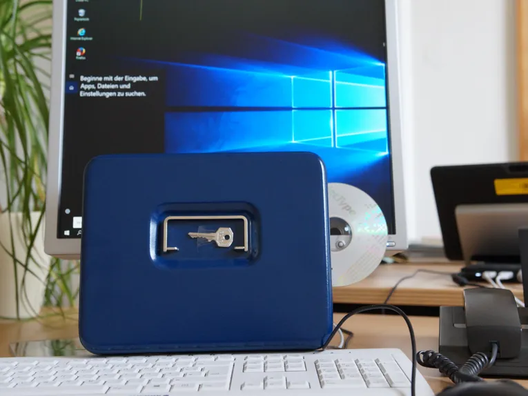 Vor einem Computer steht eine abschließbare Kassette mit einem Schlüssel.