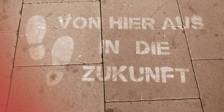 Auf einem gepflasterten Weg sind zwei Fußabdrücke aufgebracht, daneben der Schriftzug "Von hier aus in die Zukunft".