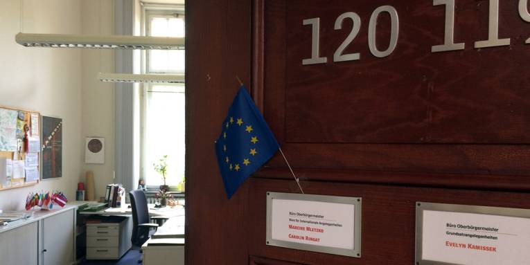Eine halb offene Bürotür mit einer kleinen Europaflagge am Türschild.